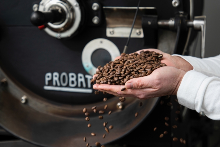 Jang Woo-young is holding coffee beans in both hands in front of the coffee bean machine