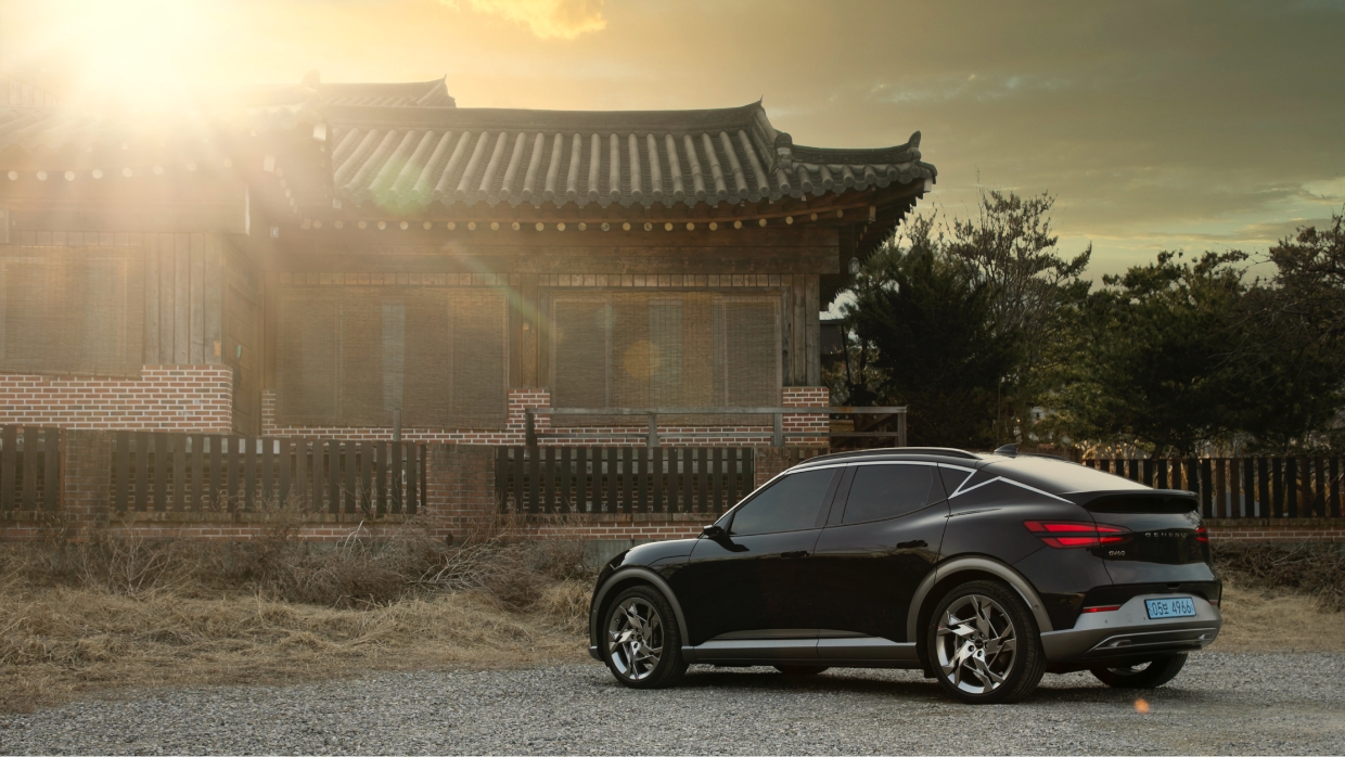 GV60 is standing in the sunset light in front of a quiet hanok, a traditional Korean building