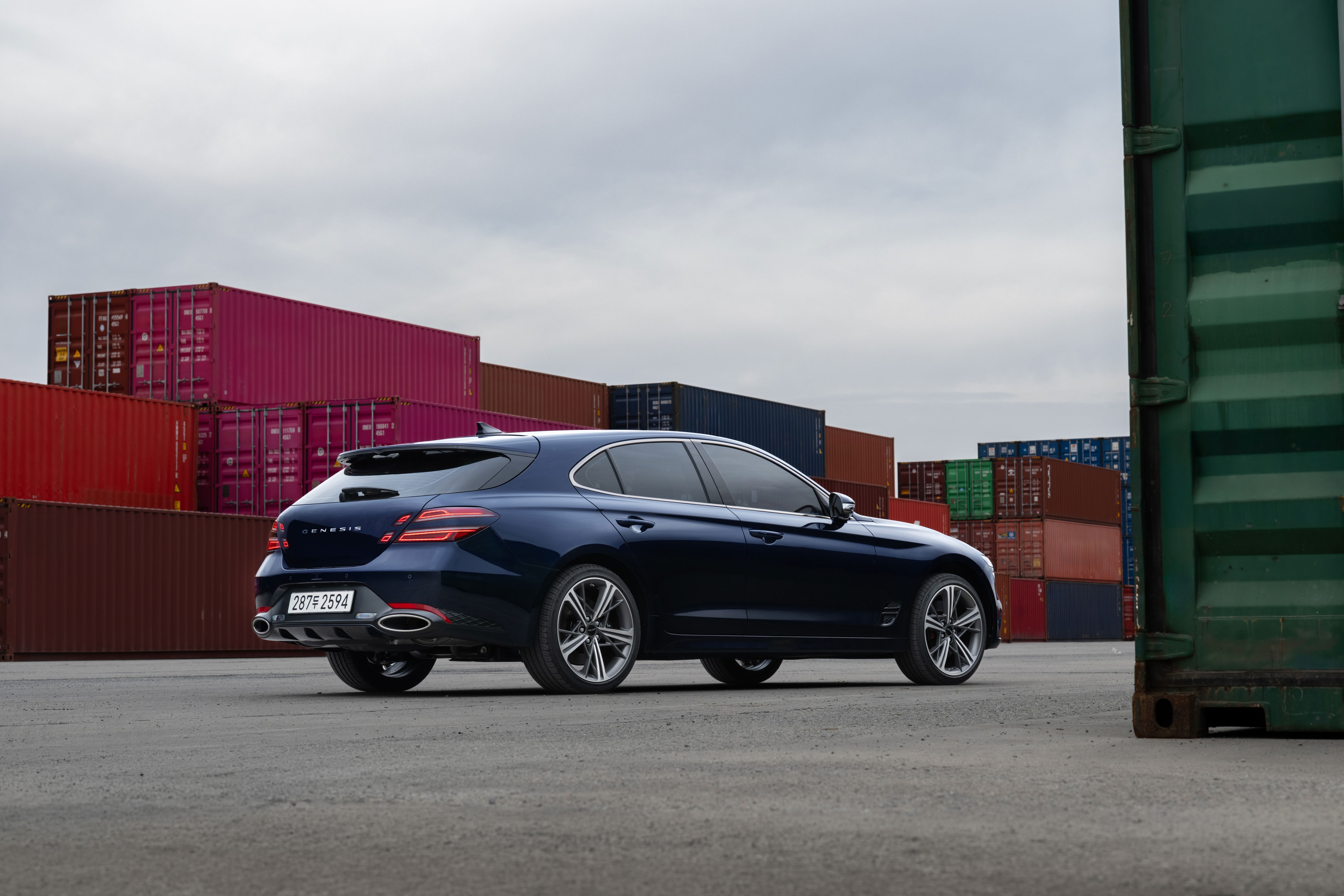 항만 컨테이너 앞에 주차된 제네시스 G70 슈팅브레이크 차량의 후측면