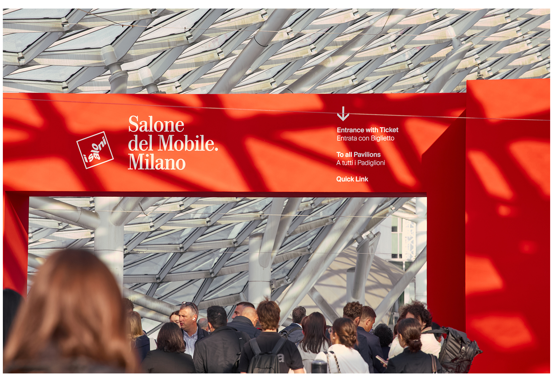 밀라노 살로네 델 모빌레 행사장 입구에 설치된 붉은 구조물 앞을 관람객들이 지나가는 모습