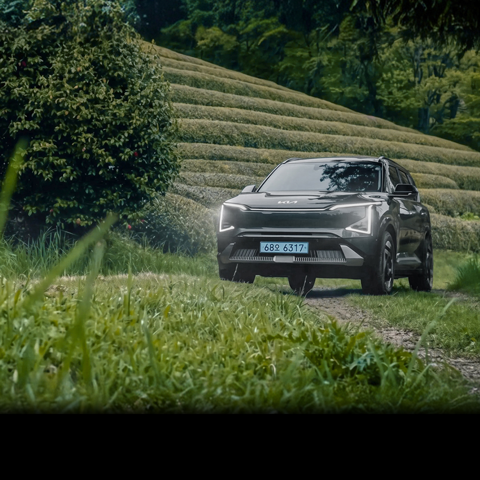 Kia EV5 driving along a road with Boseong tea fields in the background