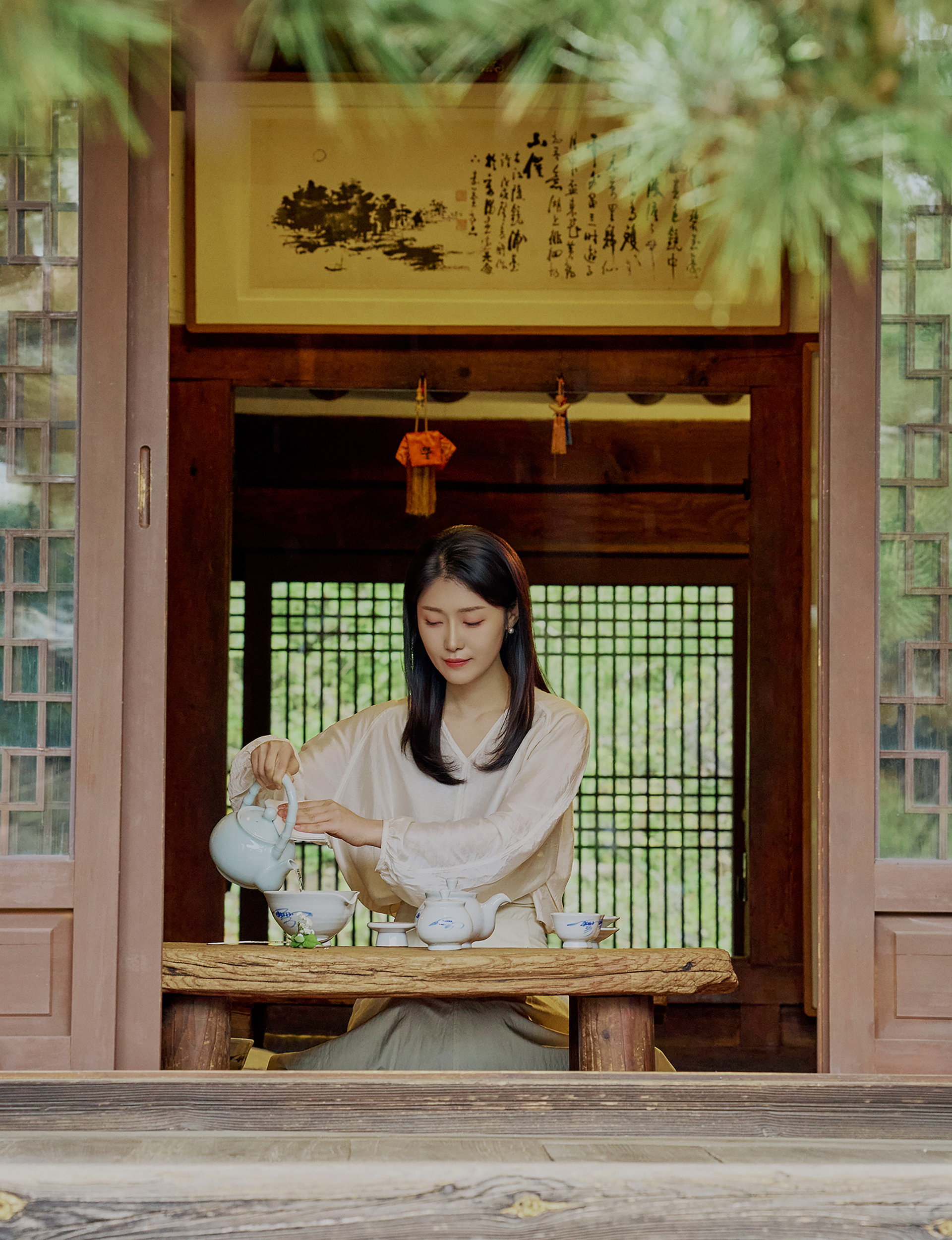 A person enjoying a traditional tea ceremony by the window of a hanok