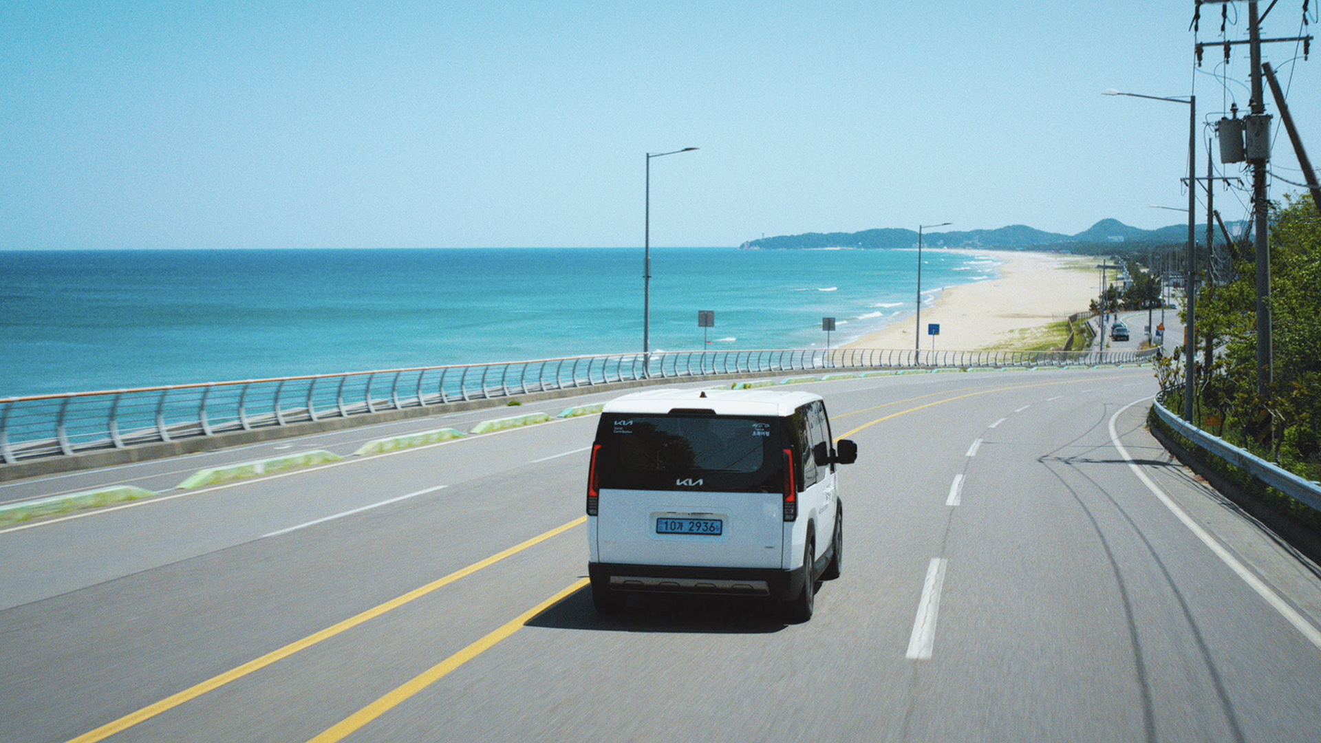 Kia PV5 WAV driving along a coastal road