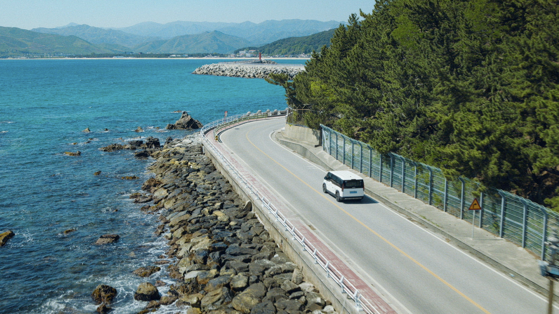 Kia PV5 WAV driving along a coastal road