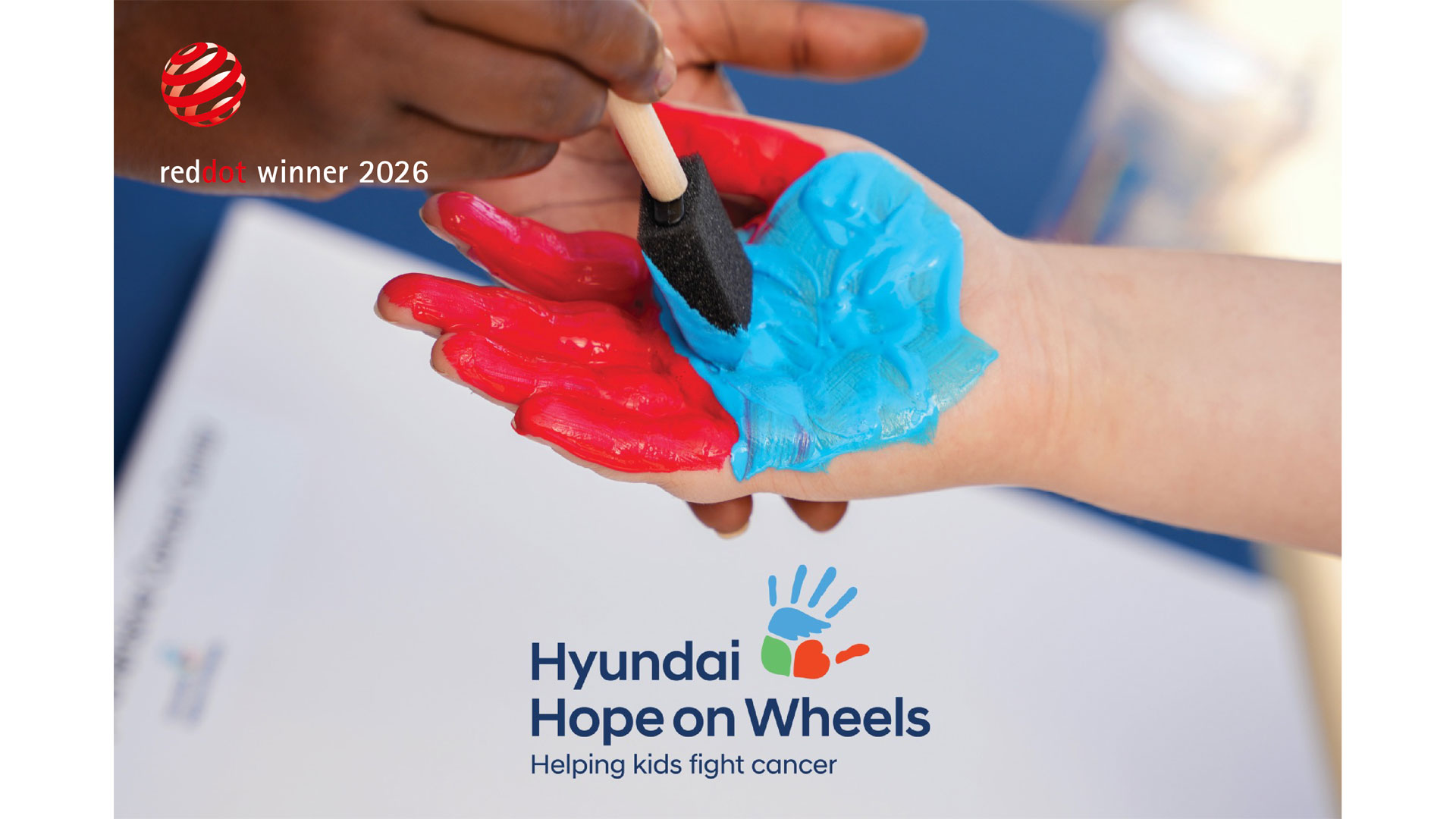 Adult applying blue paint to a child’s red-painted palm for Hyundai Hope On Wheels