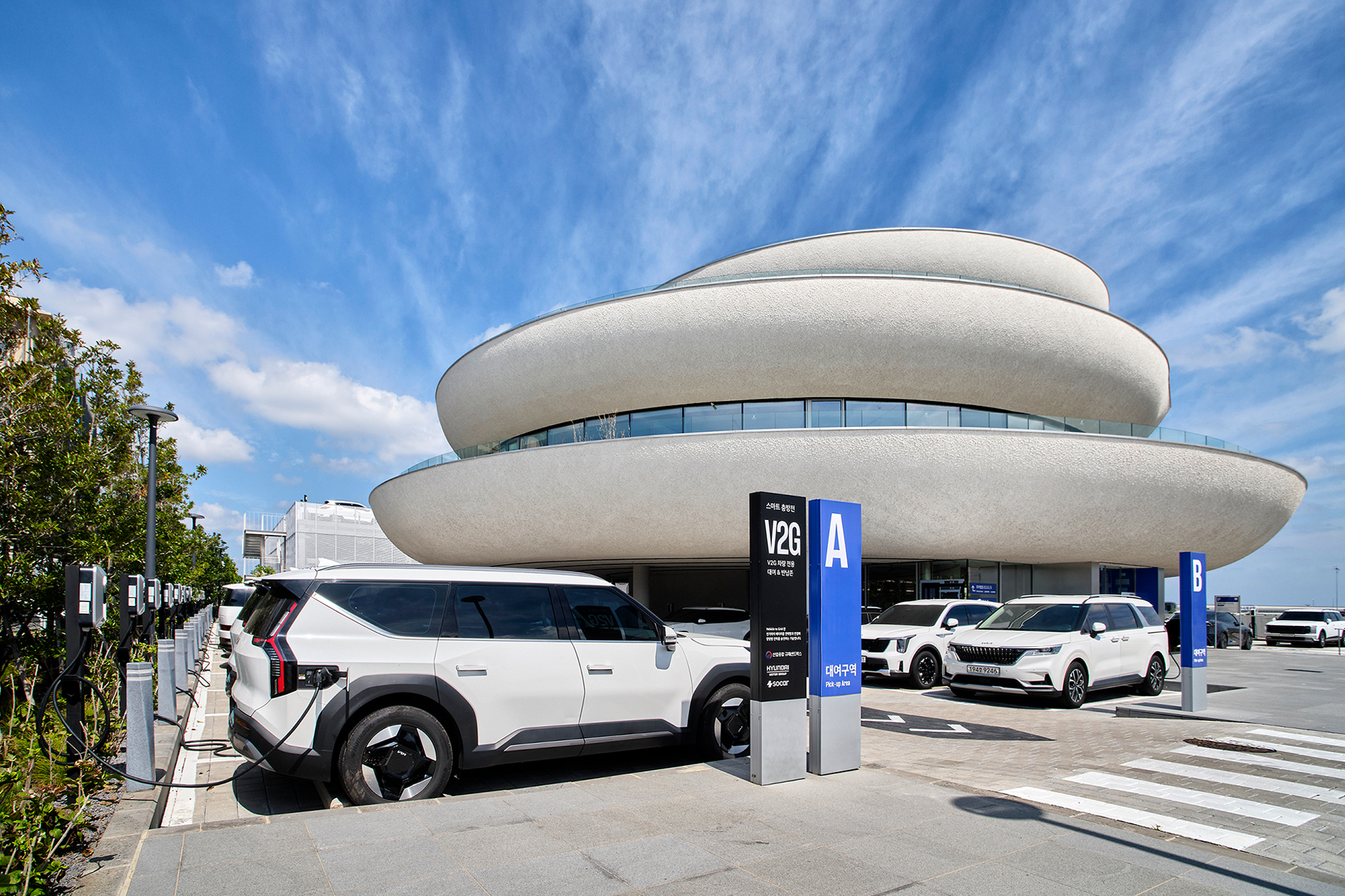 Electric vehicle parked at a charging station in front of a building on Jeju Island